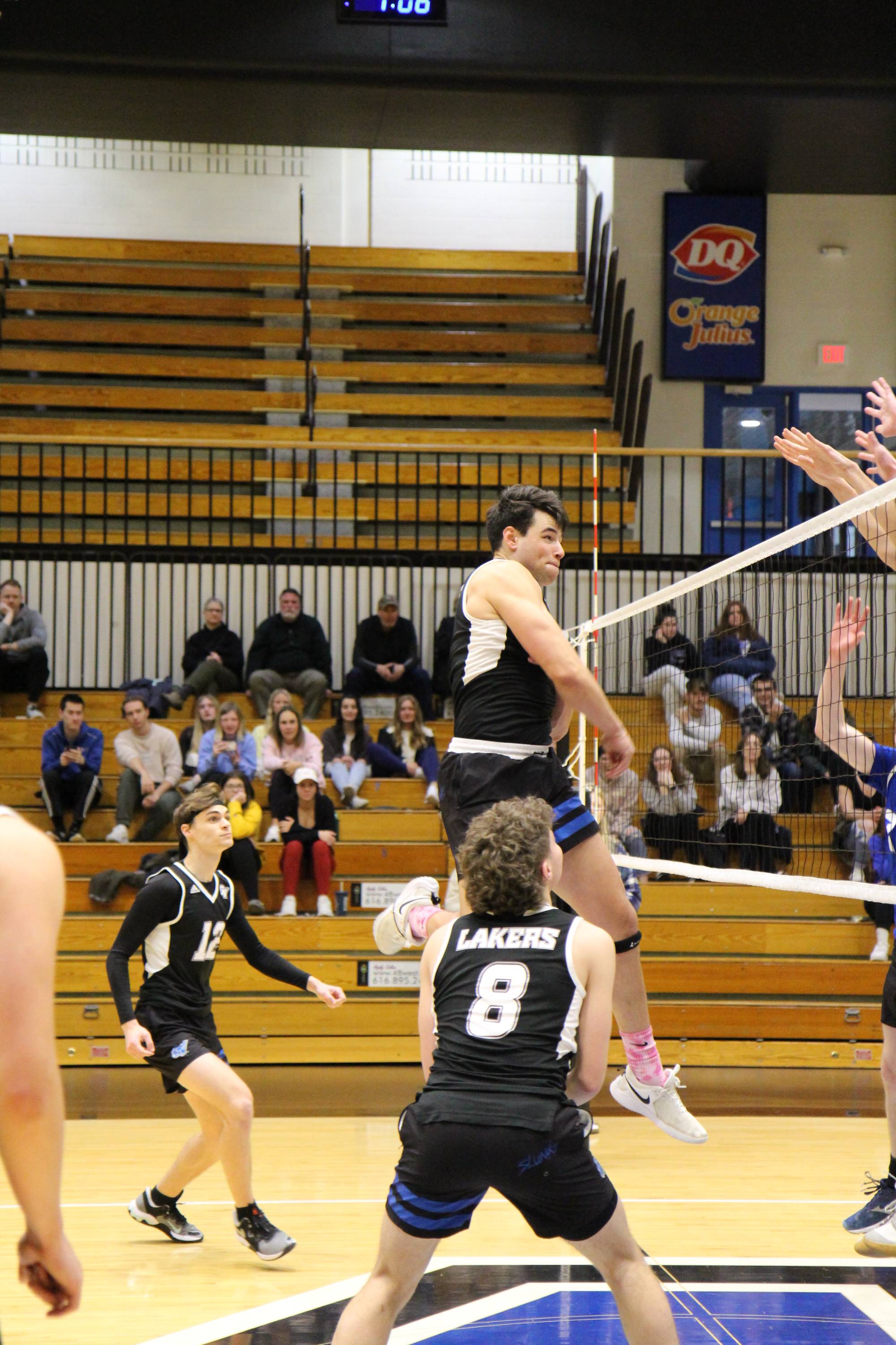 volleyball player finishing a hit with teammates surrounding him